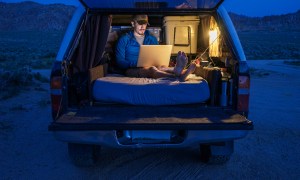 aop version 8 hiker using laptop in car trunk during vacation