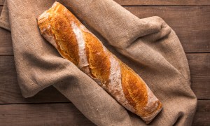 French baguette on linen bread bag on wooden counter top