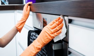 Goved hands cleaning the outside of the oven