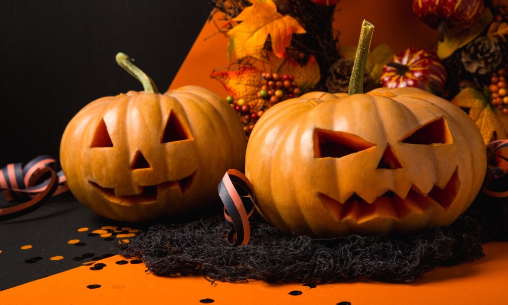 Orange pumpkins sit on top of an orange tabletop.