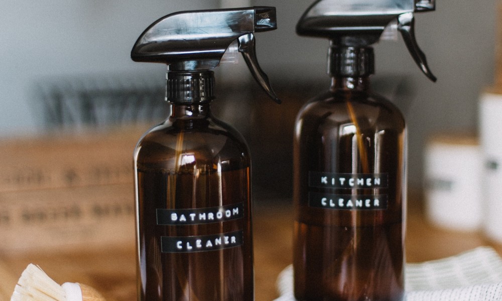 Two cleaning bottles sit on top of a wooden counter.