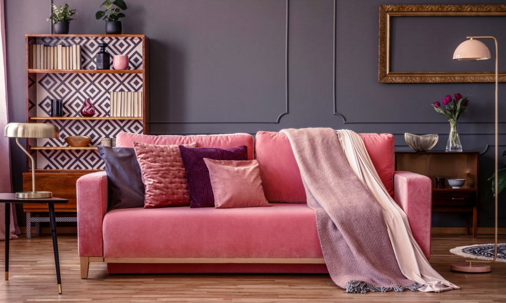 Living room with a pink couch, bookshelf, and lamps