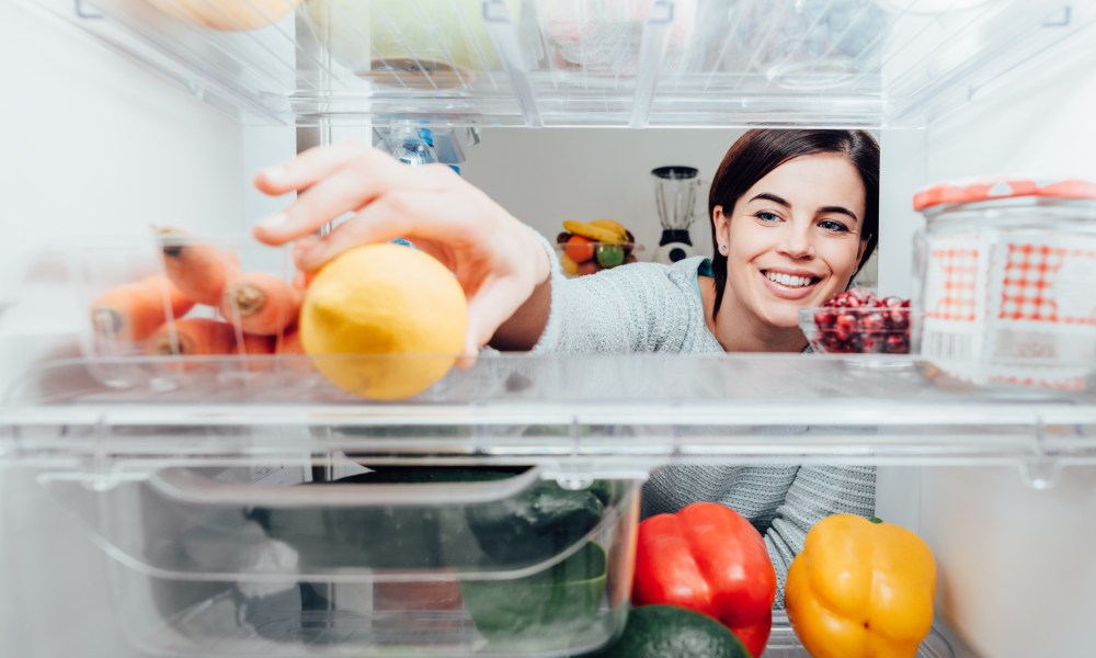 Woman opening fridge to get fruit