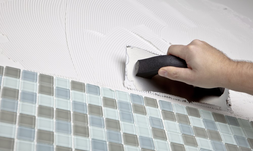 Hand applying grout to glass tile.