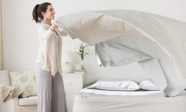Woman putting white sheets on a bed