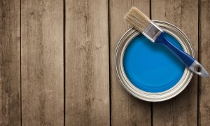 Small blue paint can with paint brush set on top.