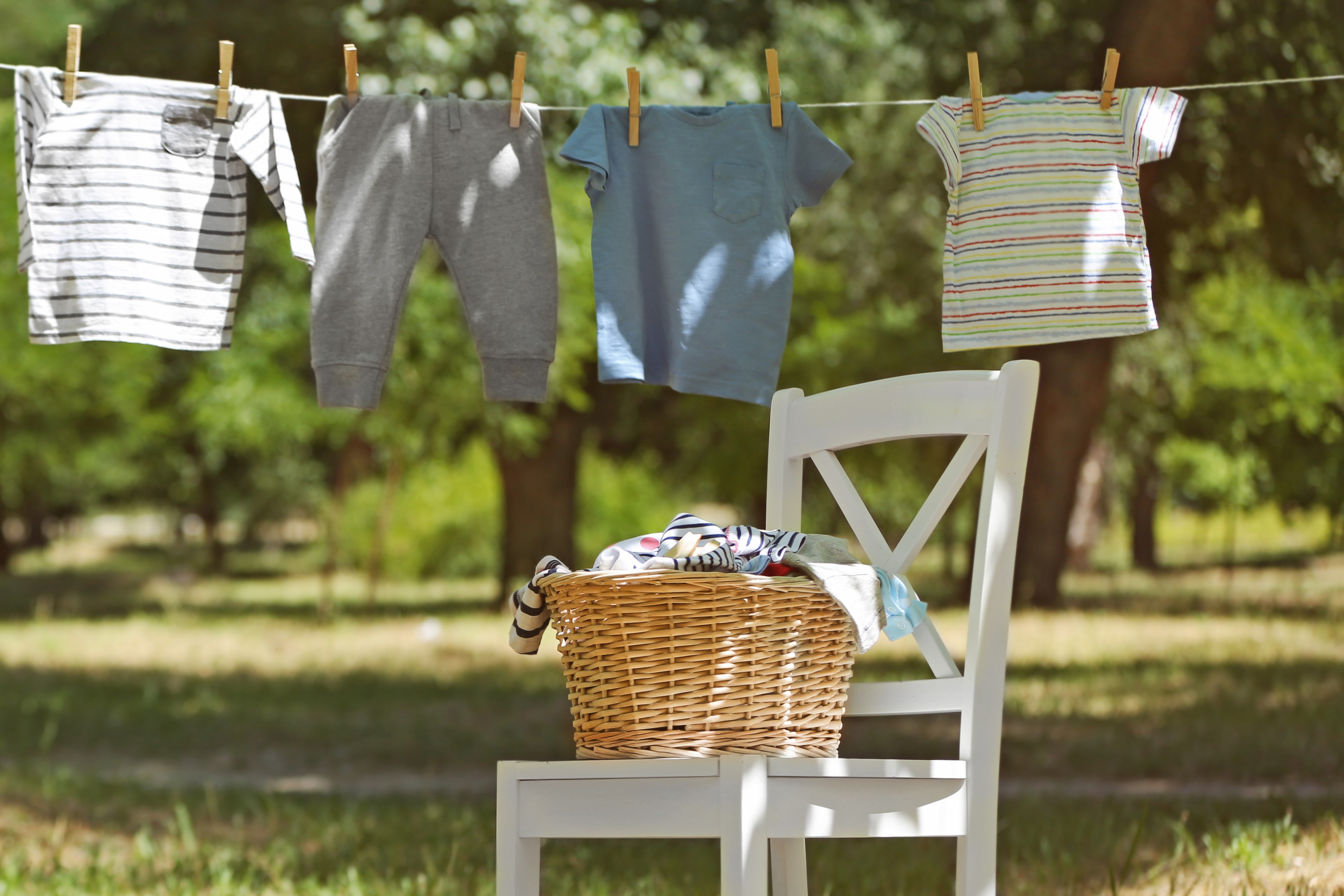 clothes drying on a line next to a white chair and wicker basket