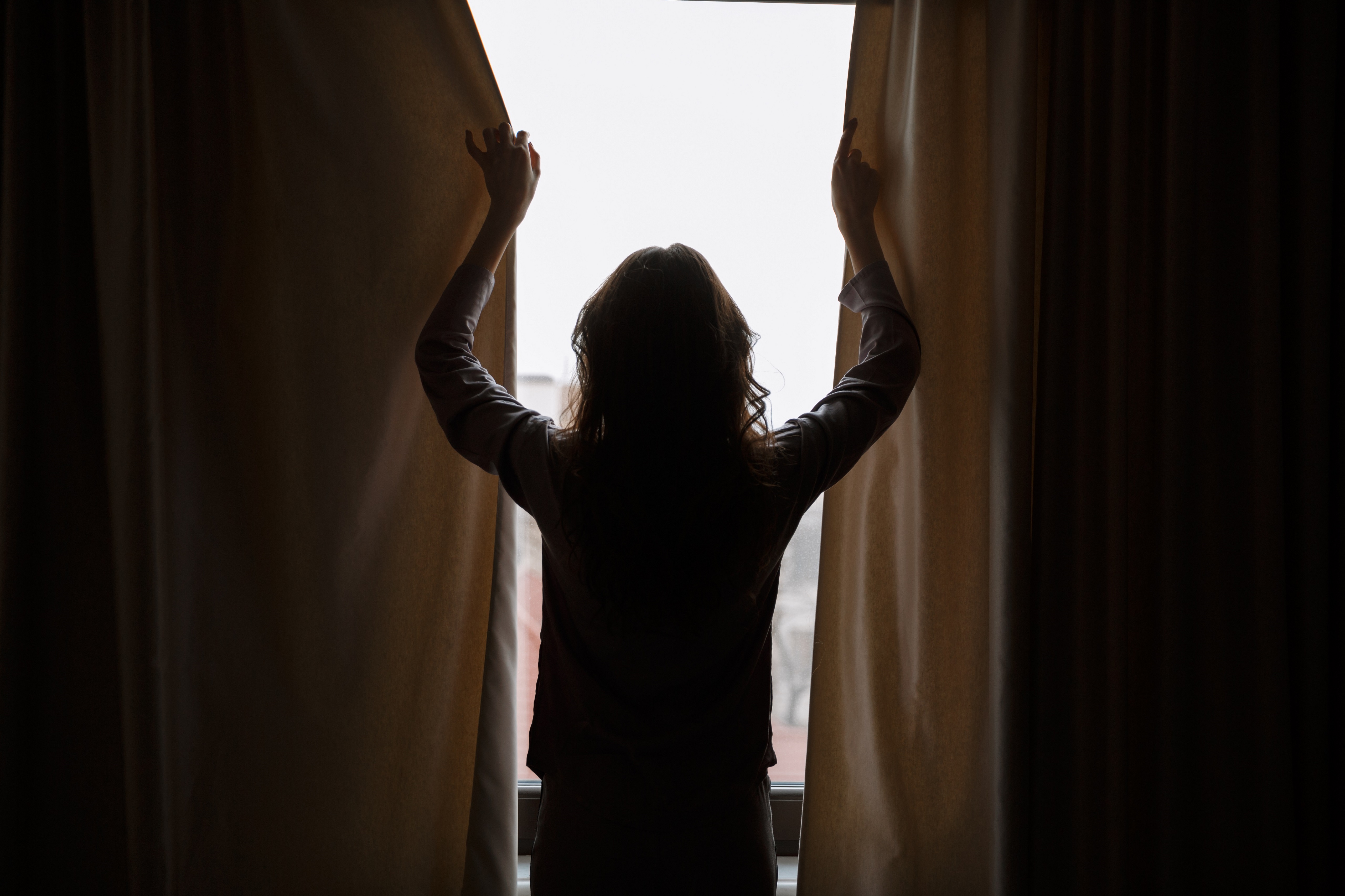 woman closing blackout curtains