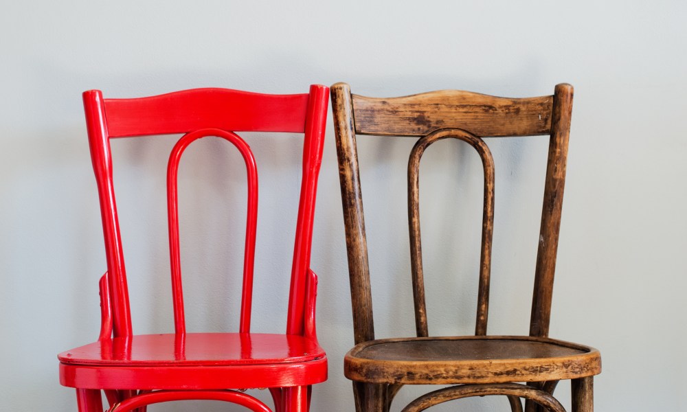 Two wooden chairs next to each other: one is painted red and one is natural wood