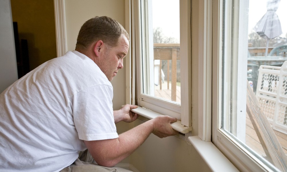 Man installing bottom of window trim