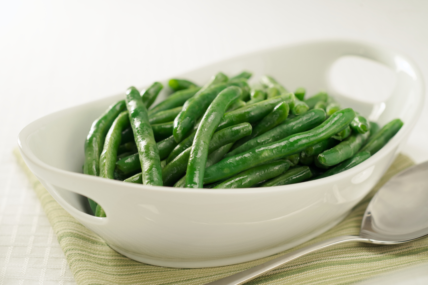 steamed green beans in white bowl with serving spoon resized