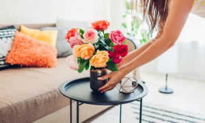 Person placing flowers in a vase on a coffee table