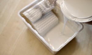 Pouring cream paint into a paint tray