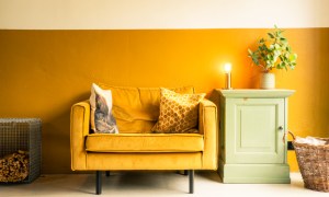 Interior of a house. Mustard yellow velvet loveseat. Living room with midcentury modern furniture. Concrete floor. Vintage carpet. Eclectic living room.