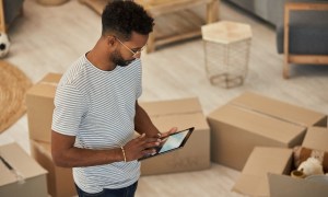 Man on iPad surrounded by moving boxes