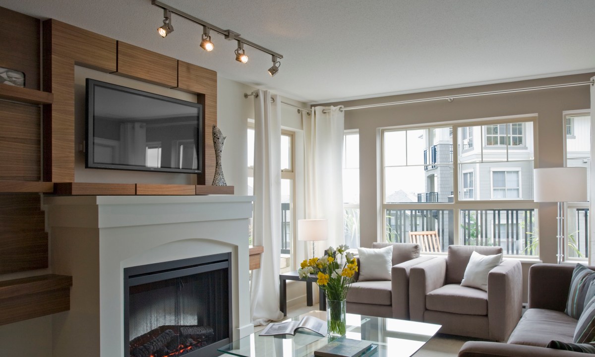 Track lighting used to emphasize tv and fireplace in a living room