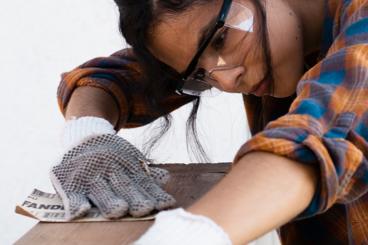Woman using sand paper to sand wood