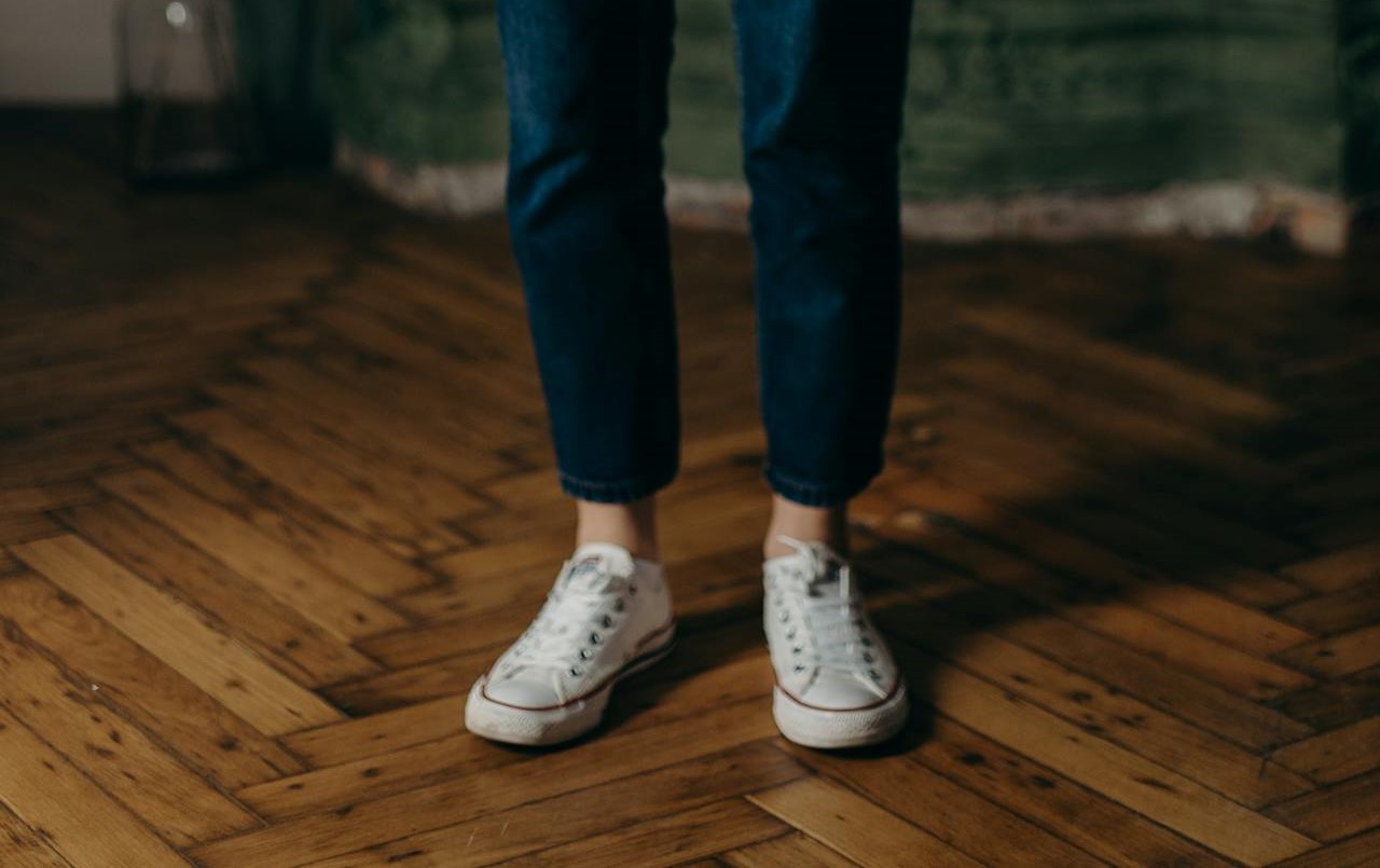person in sneakers standing on parquet floors