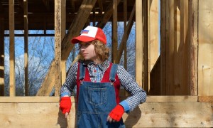 Woman posing by a house stud frame being constructed