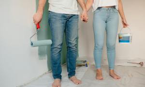 Man and woman in jeans holding hands with paint rollers