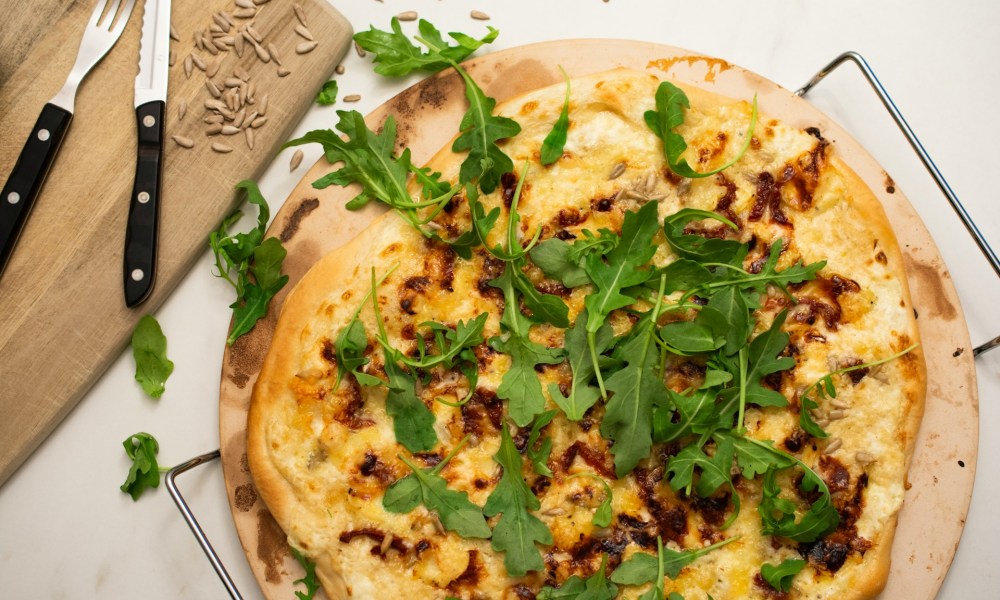 Arugula pizza on a pizza stone with handles